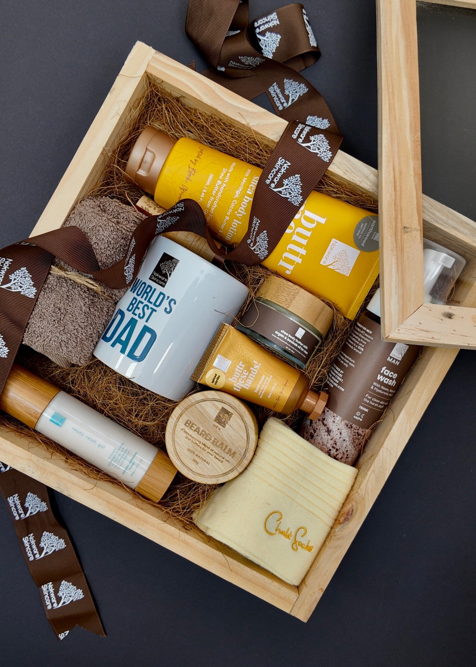 Nokware Skincare Gift box with various items including a mug labeled 'World's Best Dad' on a dark background.
